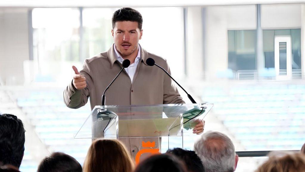 Man at a Clear Acrylic Podium Giving a Speech to an Audience in a Conference or Event Hall with Two Microphones - Especies Políticas