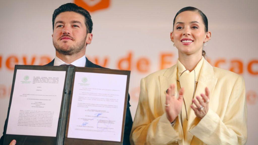 Man and Woman in Business Attire Stand on a Stage, Presenting an Open Certificate Folder with Official Documents During a Ceremony. - Especies Políticas