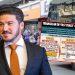 Man in a Navy Suit and Orange Tie Stands in Foreground with a Large Bus Displaying a Spanish-language Infographic About a Political Scam in the Background. - Especies Políticas