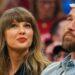 Woman with Long Light Brown Hair and Red Lipstick Looks Upward, Seated Beside a Bearded Man Wearing a Red Cap at a Crowded Event. - Especies Políticas