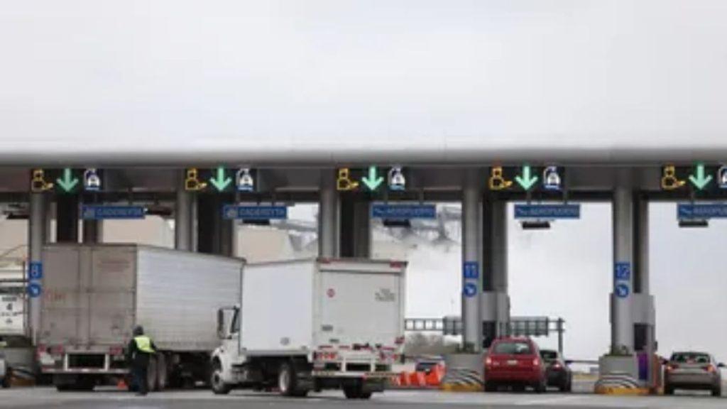 Vehicles, Including Trucks and Cars, Wait at a Toll Plaza Under a Covered Structure. - Especies Políticas