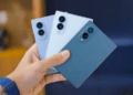 Person Holding Three Smartphones in Blue Shades, Showing Back with Triple-camera Modules on Each Phone. - Especies Políticas