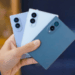Person Holding Three Smartphones in Blue Shades, Showing Back with Triple-camera Modules on Each Phone. - Especies Políticas